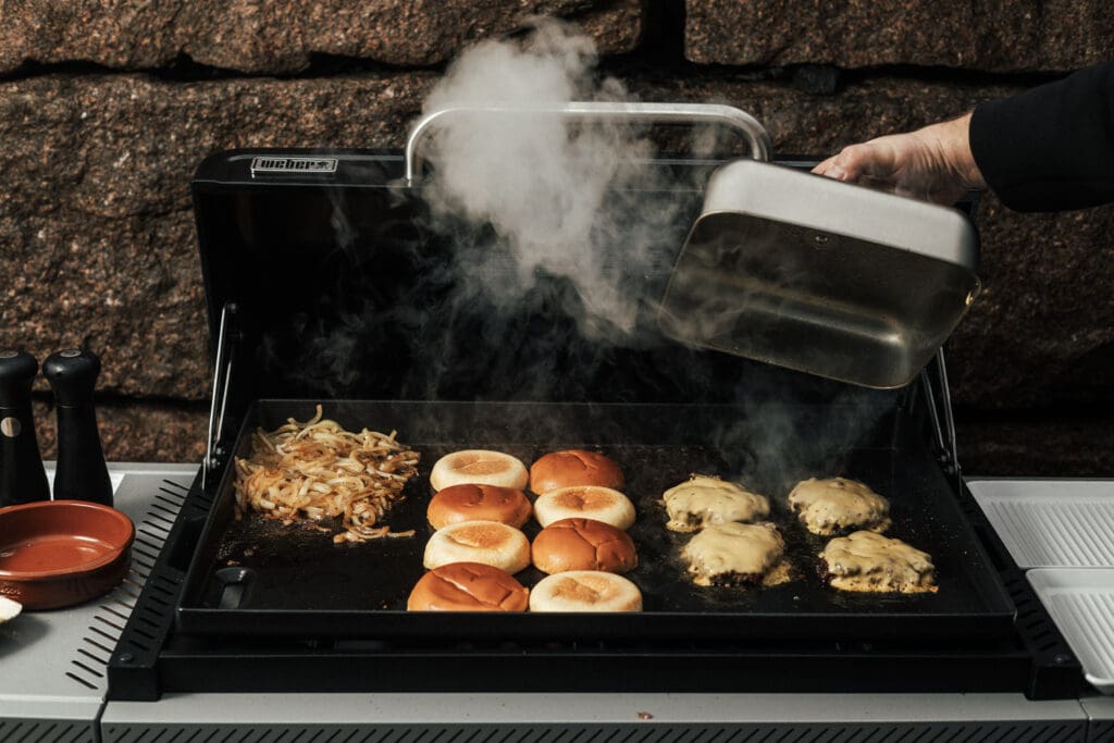 Weber Slate 71cm GPD med cheeseburgere, burgerbrød og løk.